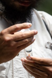 A close-up shot of a man's hands holding up a plastic syringe.