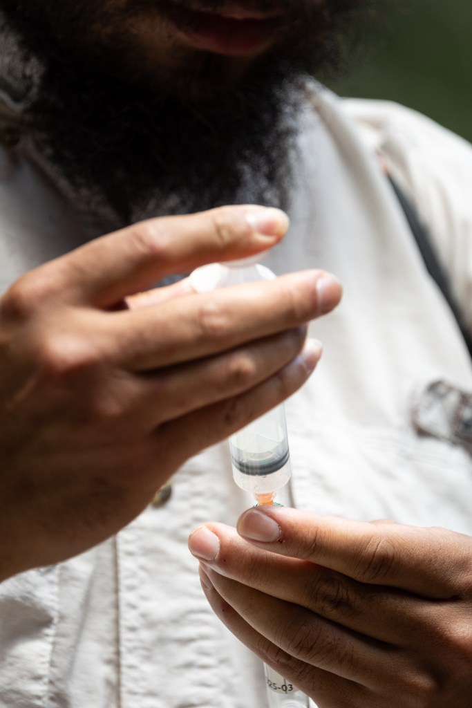 A close-up shot of a man's hands holding up a plastic syringe.