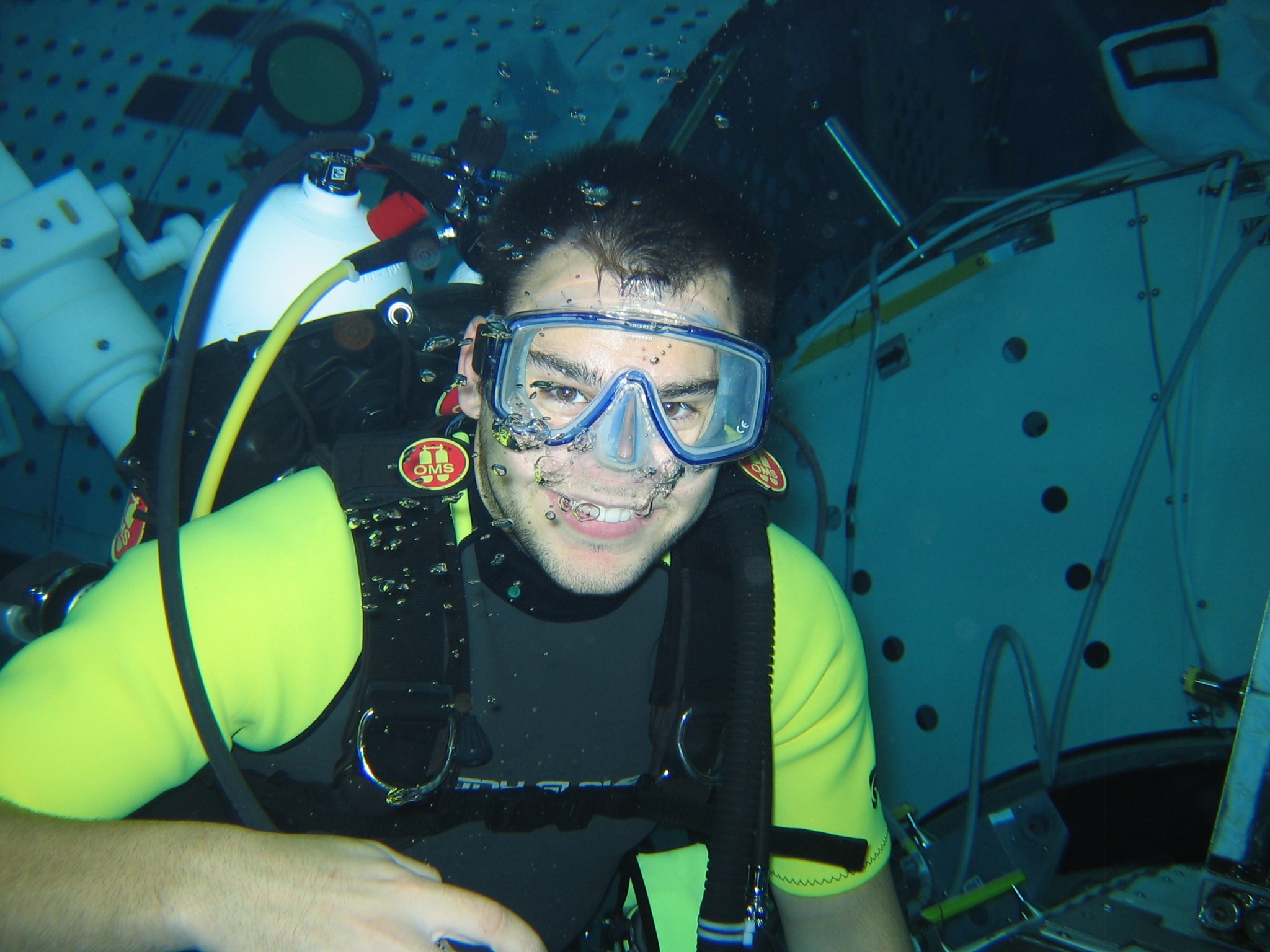 Underwater image of a man wearing scuba gear, smiling at the camera, with a mockup of the International Space Station in the background.