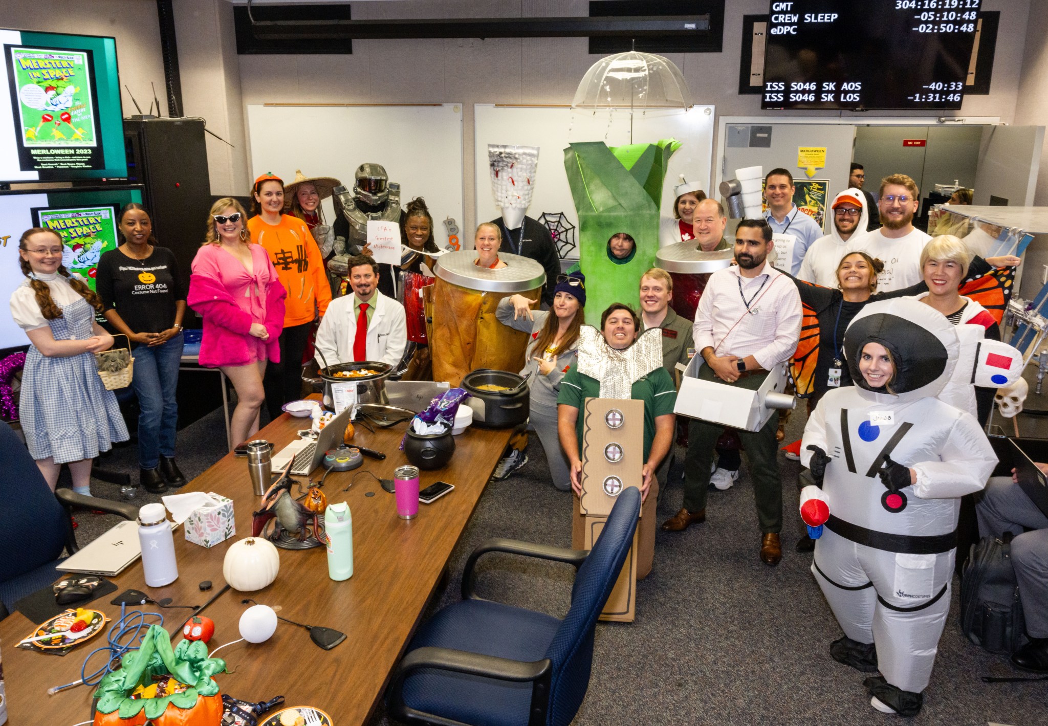 A group of people dressed in Halloween costumes pose inside of a room.