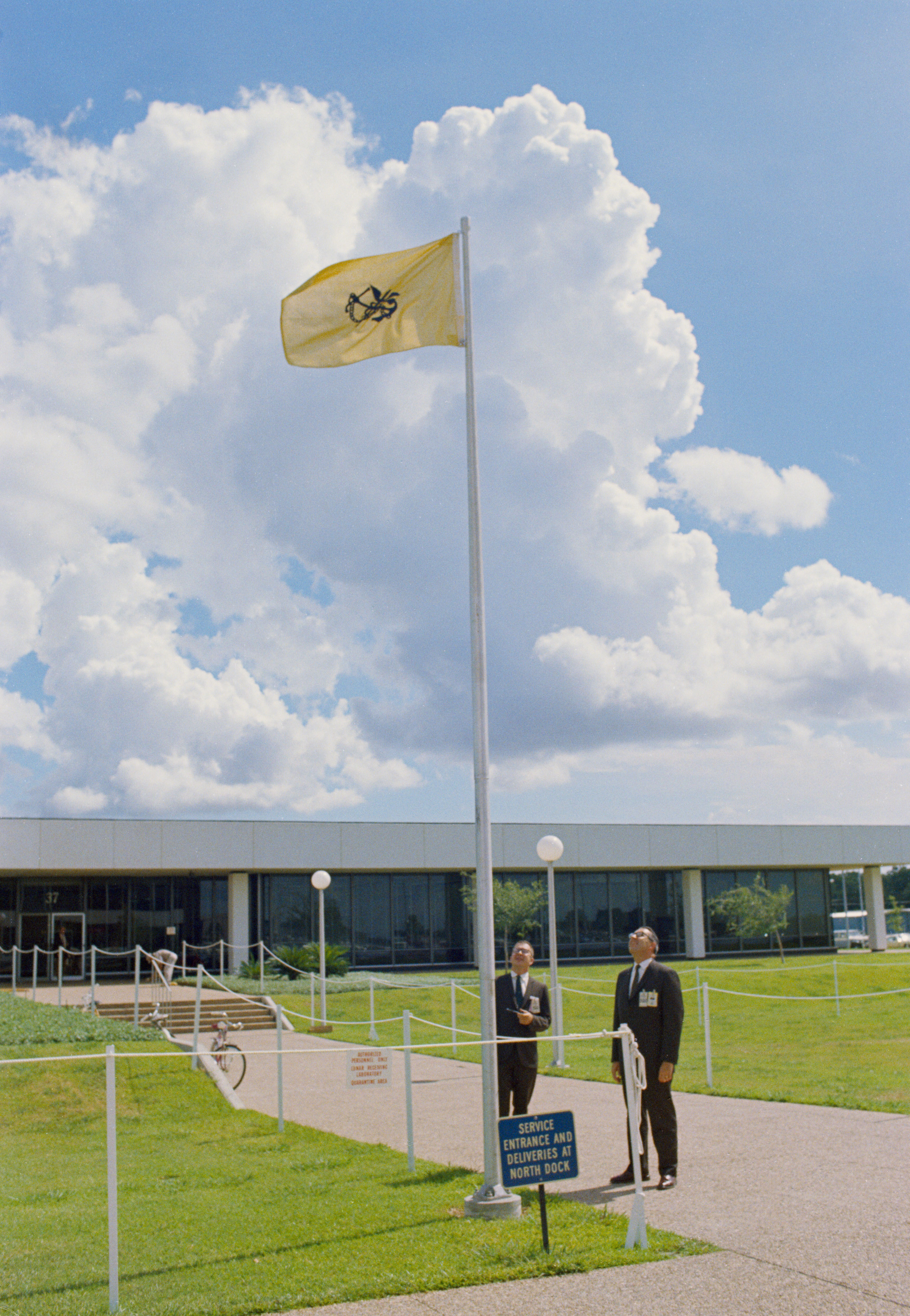 Dr. Charles A. Berry, Director, Medical Research and Operations, and Dr. Walter W. Kemmerer, Chief, Preventive Medicine Div., are pictured looking at the Quarantine Flag being flown outside the Bldg. 37 Lunar Receiving Laboratory where the Apollo 11 Astronauts are temporarily housed.