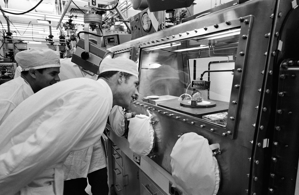 Astronaut David R. Scott, right, Commander of the Apollo 15 mission, gets a close look at the sample referred to as "Genesis Rock" in the Non-Sterile Nitrogen Processing Line (NNPL) in the Lunar Receiving Laboratory (LRL) at the Manned Spacecraft Center (MSC).