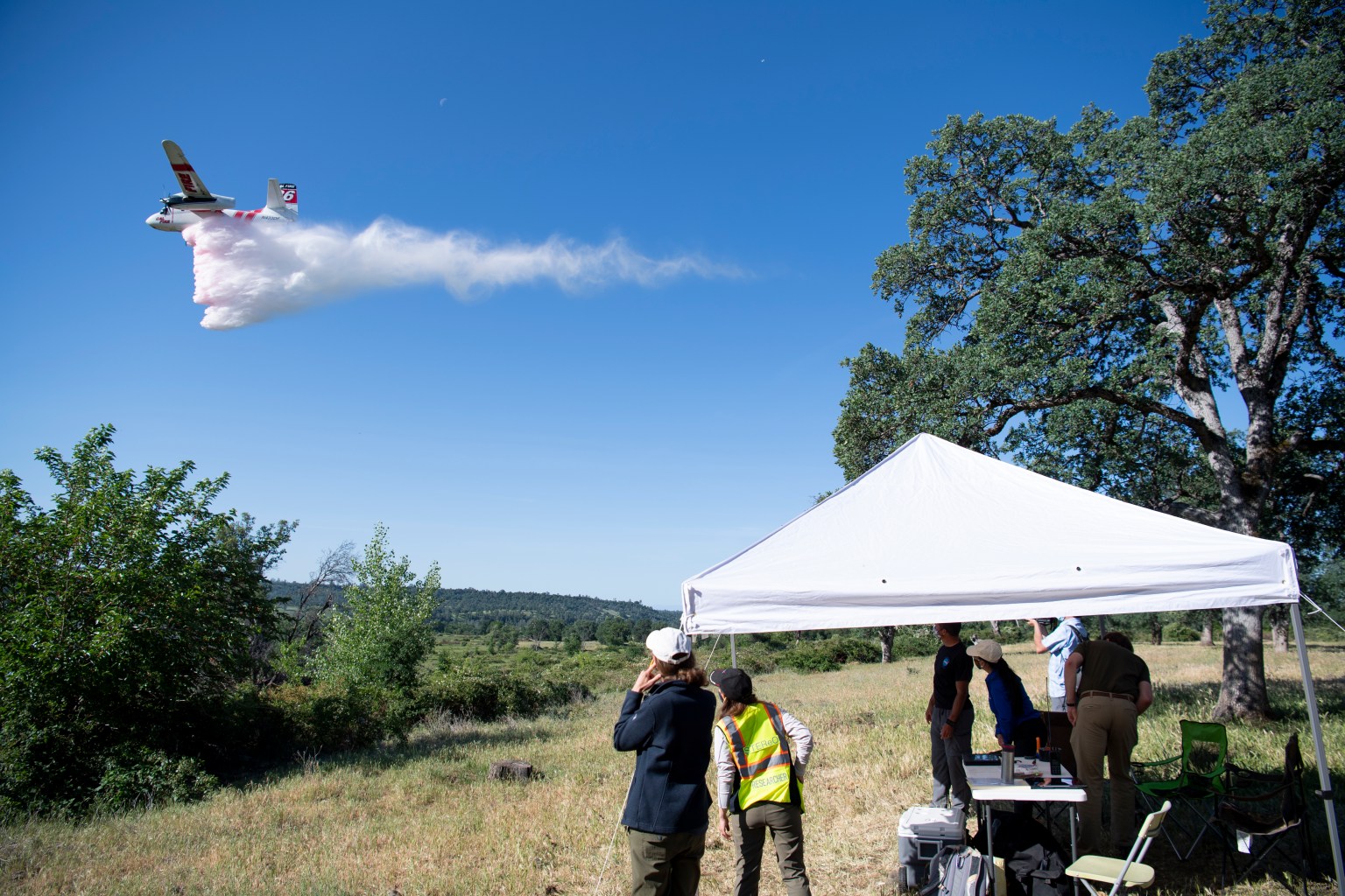 NASA scientists watch as a Cal Fire S2-T airtanker drops water on a simulated wildfire, Tuesday, May 4, 2021 as Cal Fire conducts aerial fire fighting training exercises near Redding, California.