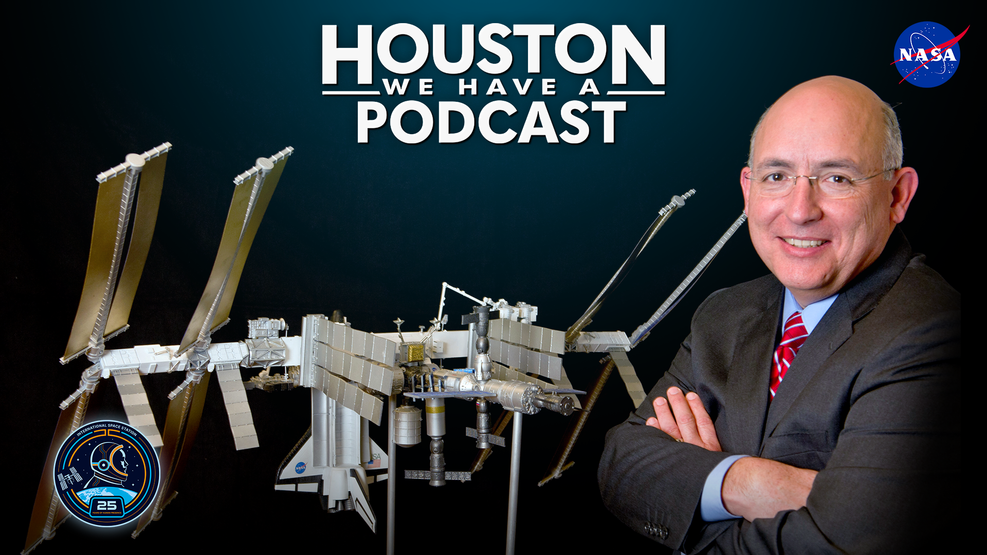 HWHAP Ep. 405. Mike Suffredini crosses his arms in front of a model of the International Space Station.