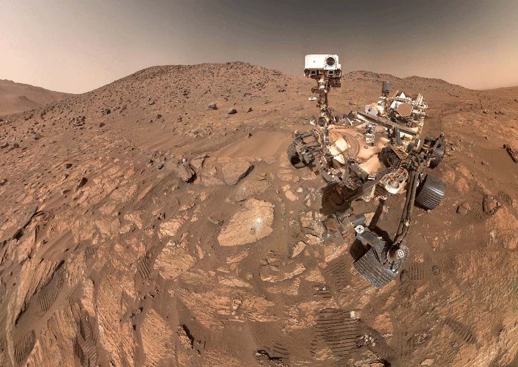 Mars'ta çekilen bir selfie'de, NASA'nın Perseverance keşif aracı - bu animasyonlu görüntüde hareket eden bir kameraya sahip altı tekerlekli bir robot - Kırmızı Gezegen'in manzarasıyla birlikte görülüyor.