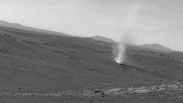A dust devil touches down on the Martian surface in this black-and-white image.