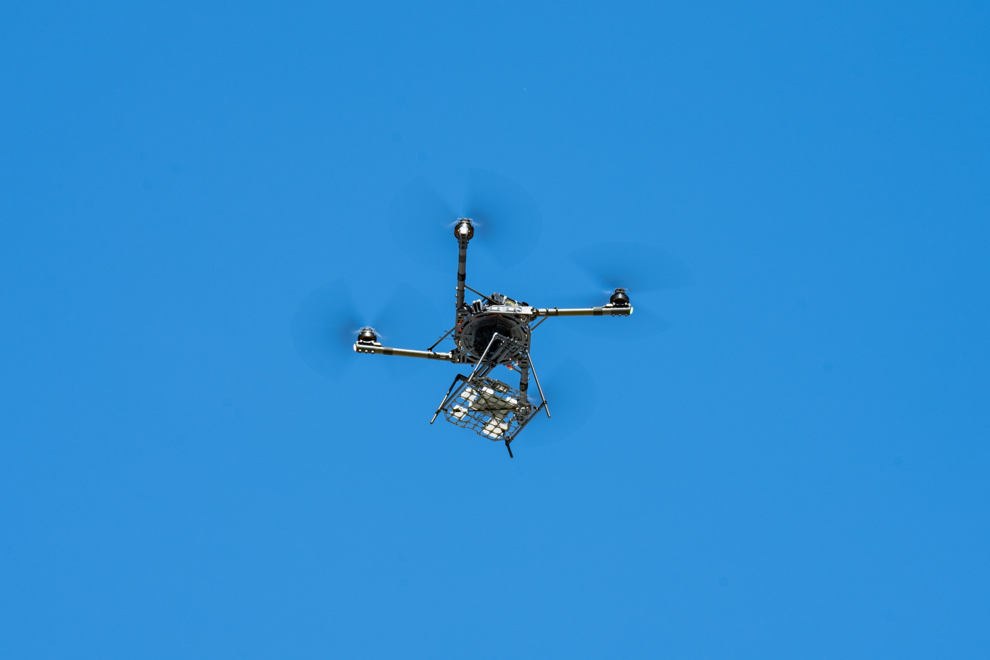 A single drone is pictured flying against a blue sky.