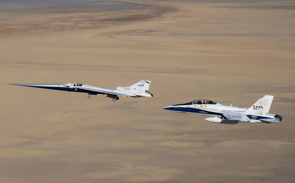 NASA’s X-59 flies above the Mojave Desert with a NASA F-15 chase aircraft nearby.