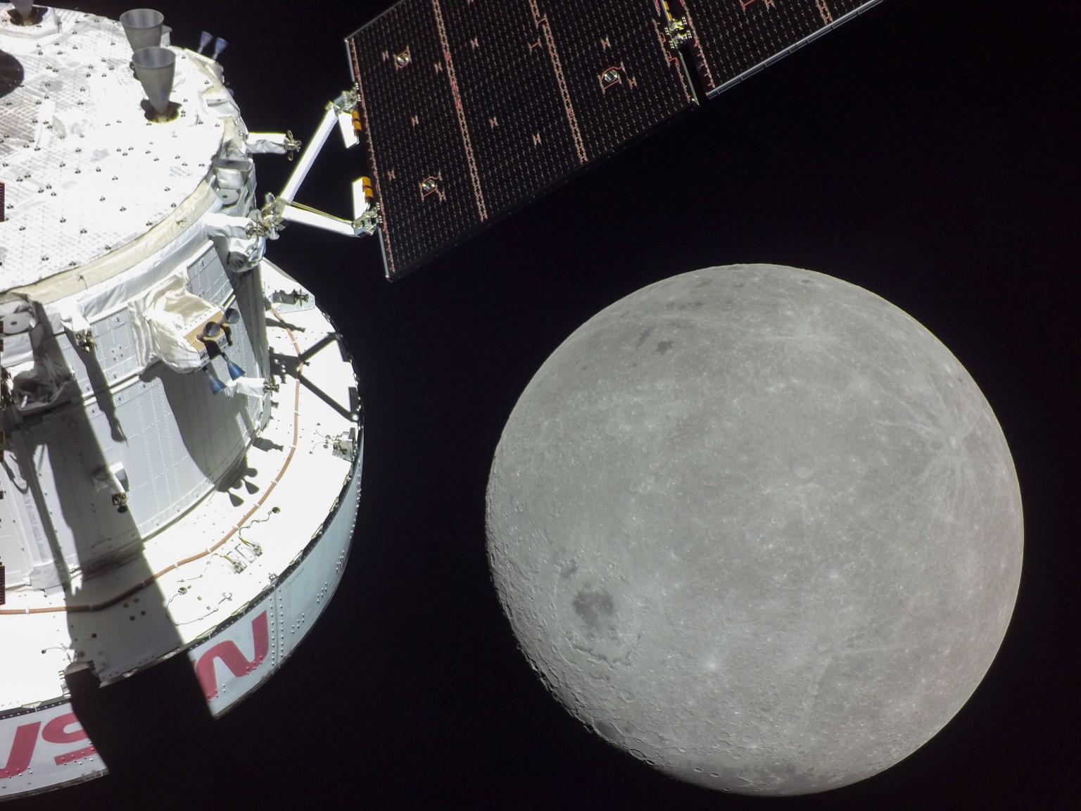 A portion of the far side of the Moon looms large just beyond the Orion spacecraft in this image taken on the sixth day of the Artemis I mission by a camera on the tip of one of Orion’s solar arrays.