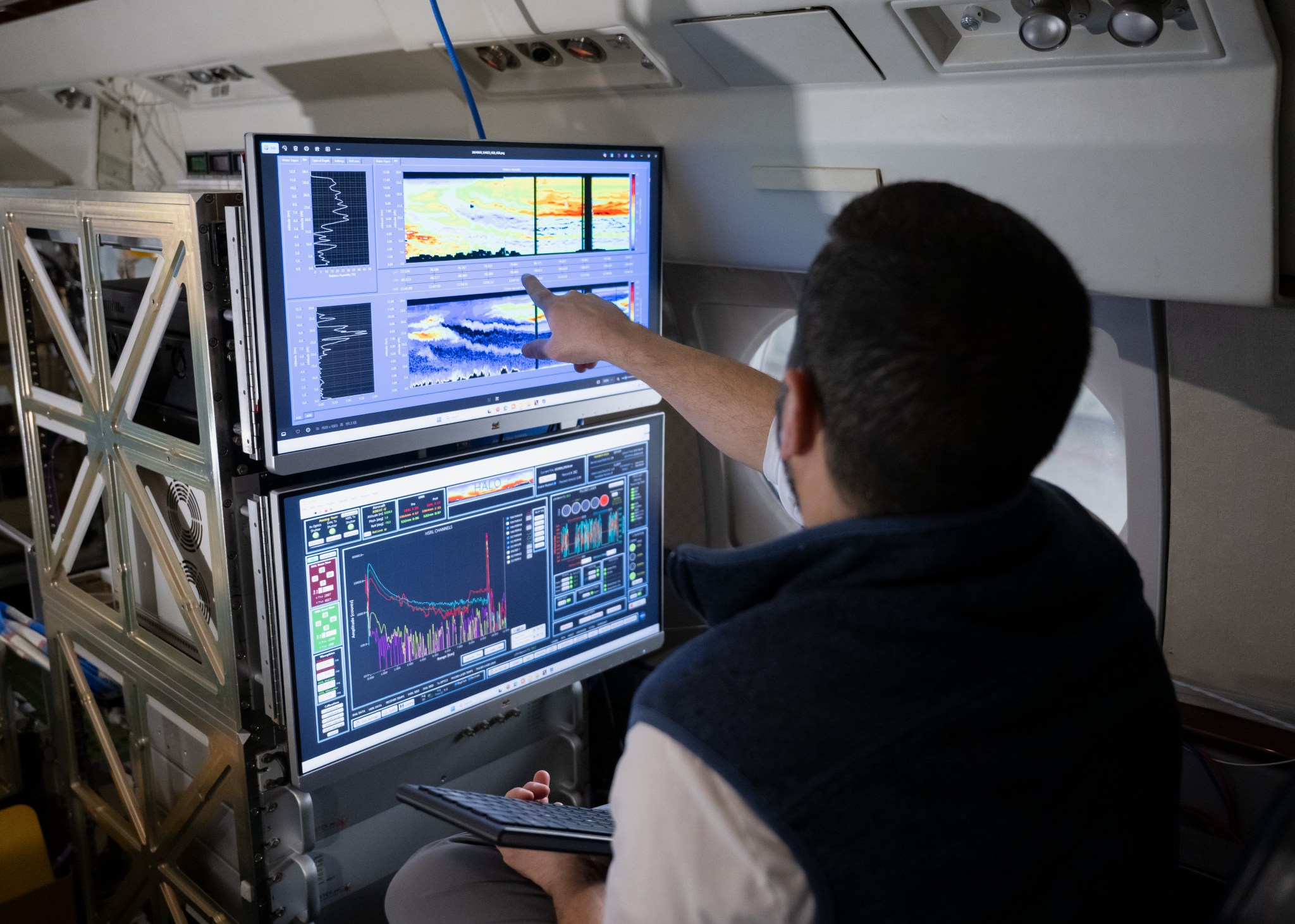 Two computer monitors are shown from the perspective of looking over a researcher's shoulder. The screens show colorful graphs representing smoke and aerosol measurements from previous missions with the HALO lidar instrument.