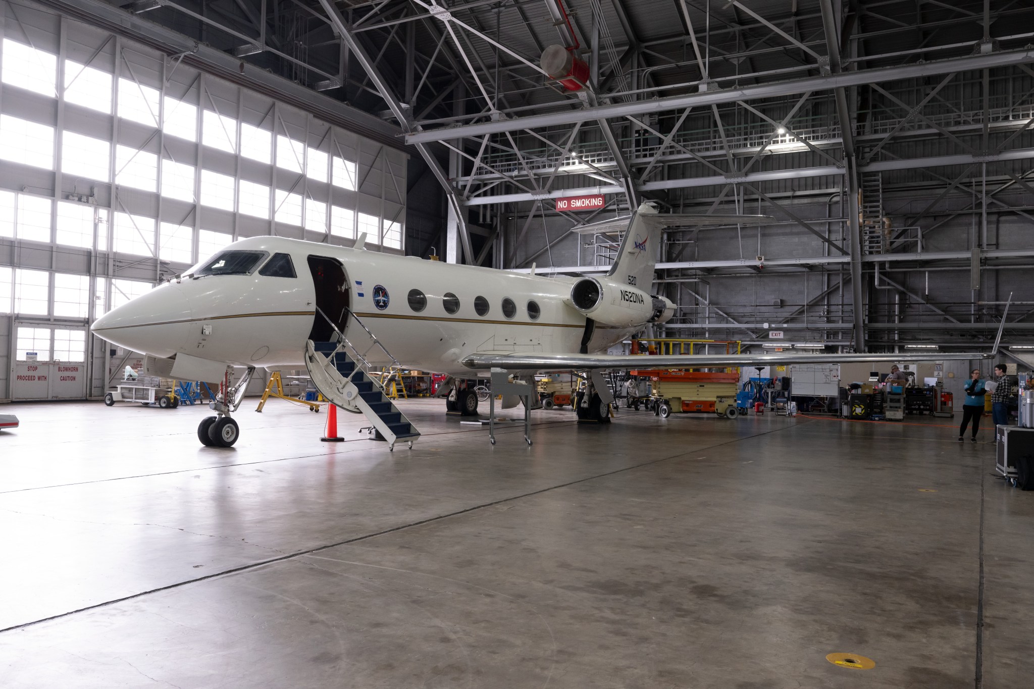 An aircraft is shown parked inside the hangar at NASA's Langley Research Center with the bay door windows backlit behind the plane.