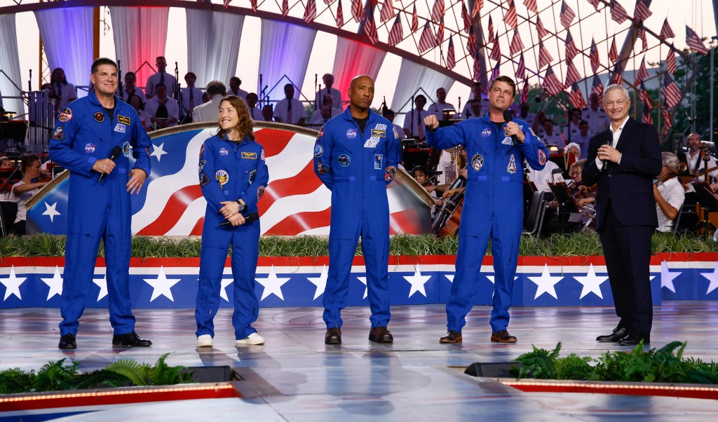 CSA (Canadian Space Agency) astronaut Jeremy Hansen, mission specialist; left, and NASA astronauts Christina Koch, mission specialist; Victor Glover, pilot; Reid Wiseman, commander; and actor Gary Sinise, right, during the “A Capitol Fourth” concert, Saturday, July 4, 2026, on the National Mall in Washington, D.C