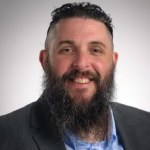 business portrait of a man with dark hair and a beard