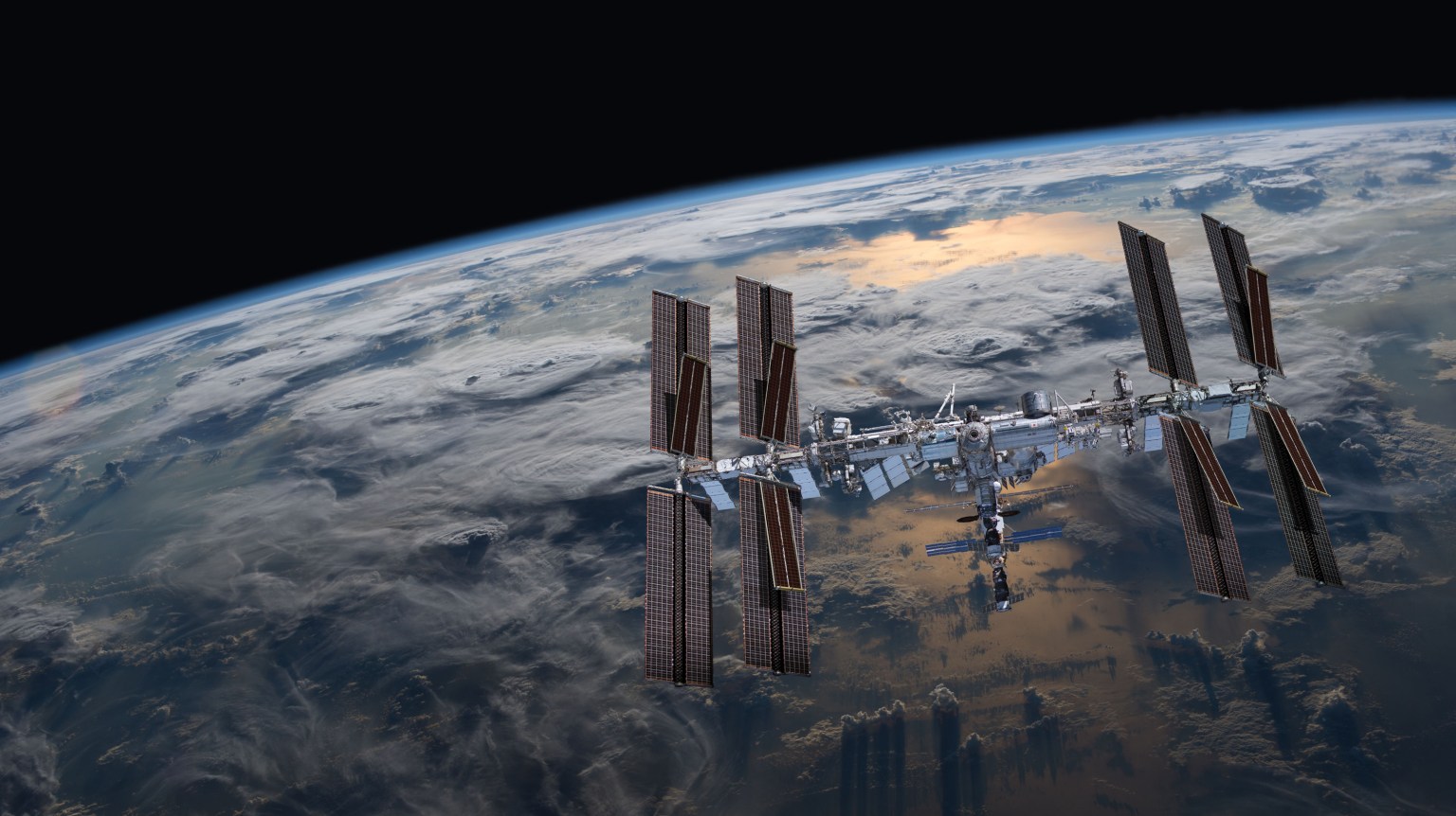 A picture of the International Space Station in front of a shot of Earth's horizon.