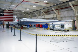 A blue and white supersonic jet with red trim sits inside a newly renovated hangar.