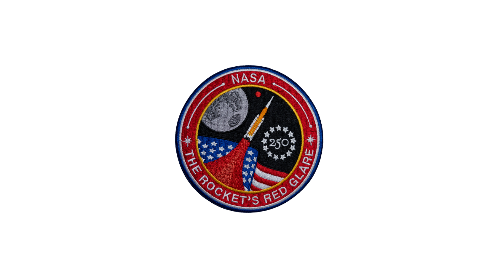 Circular astronaut mission patch with a black background, silver border, and bold Freedom 250 lettering in red and white. The design features a stylized American flag sweeping across the patch, and the Space Launch System rocket launching in the middle. In the distance, a small red circle hovers to the right behind the Moon, symbolizing the Artemis Moon to Mars missions. The bottom of the patch reads "The Rocket's Red Glare," and the America 250 logo appears to the right of the rocket, inside a circle of 13 stars, symbolizing America's 250th anniversary and future space exploration.