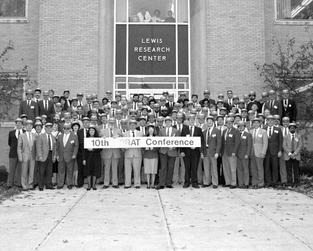 A large group of people posing for a picture holding a sign that says "10th SPRAT Conference"