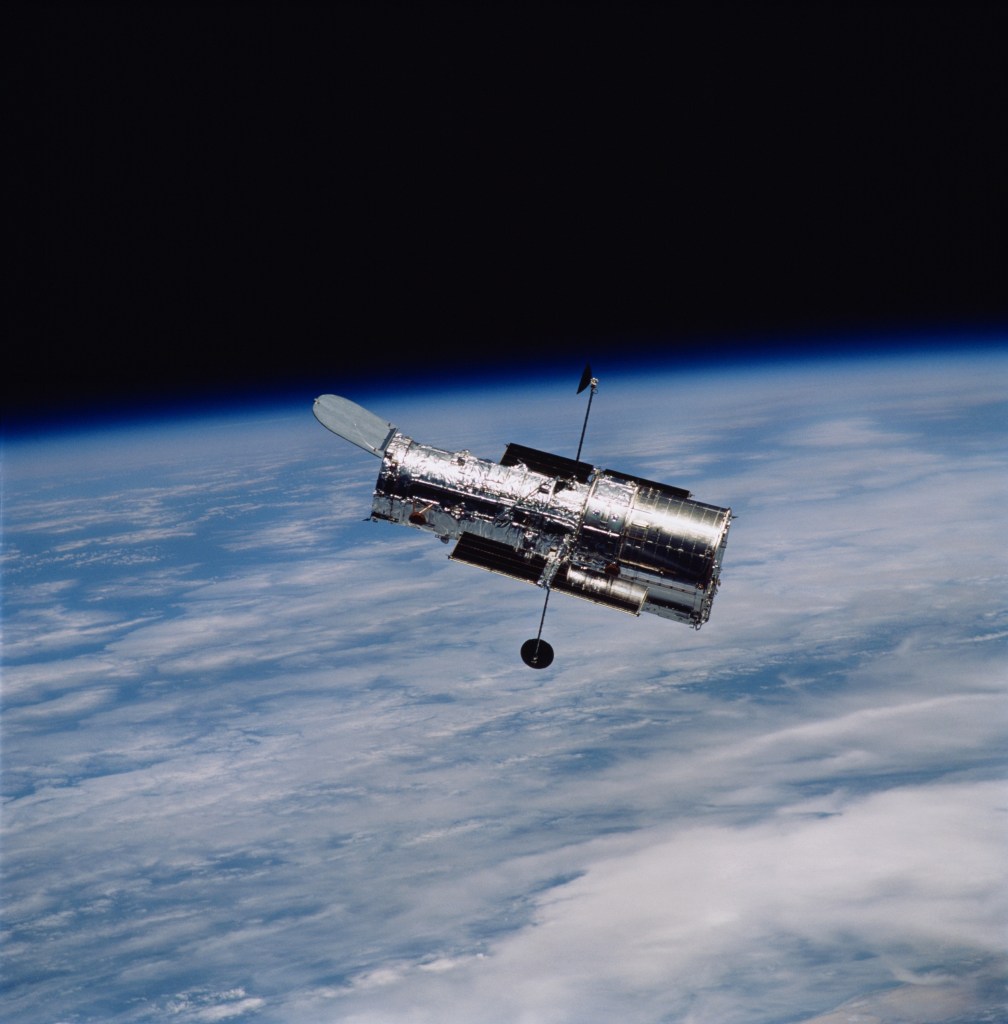 Hubble Space Telescope in space with Earth in the background below and the black background of space behind
