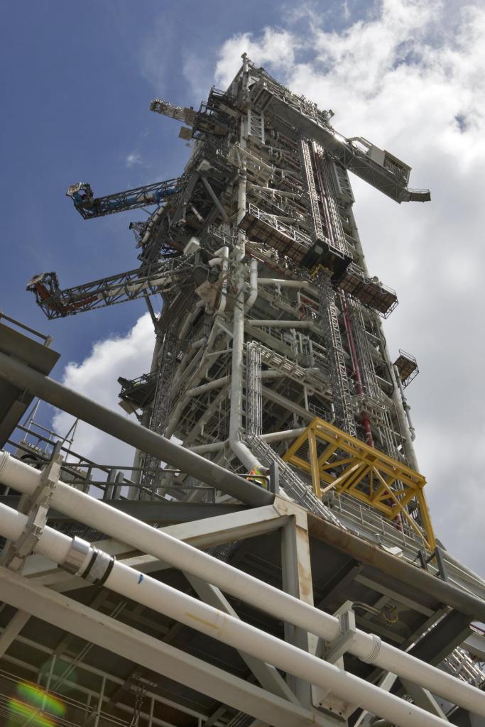 A swing test of the Orion crew access arm, top right, is in progress on the mobile launcher at NASA's Kennedy Space Center in Florida, on Aug. 21, 2018. The crew access arm is located at about the 274-foot level on the mobile launcher tower. It will rotate from its retracted position and interface with the Orion crew hatch location to provide entry to the Orion crew module. Exploration Ground Systems extended all of the launch umbilicals on the ML tower to test their functionality before the mobile launcher, atop crawler-transporter 2, is moved to Launch Pad 39B and the Vehicle Assembly Building.
