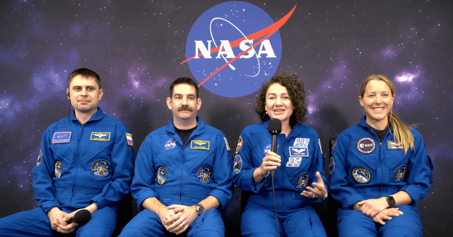 Image shows a NASA insignia in the background while four astronauts in blue flight suits sit and speak virtually to the media inside Astronaut Crew Quarters at NASA's Kennedy Space Center in Florida on Sunday, Feb. 8, 2026. Photo credit: NASA