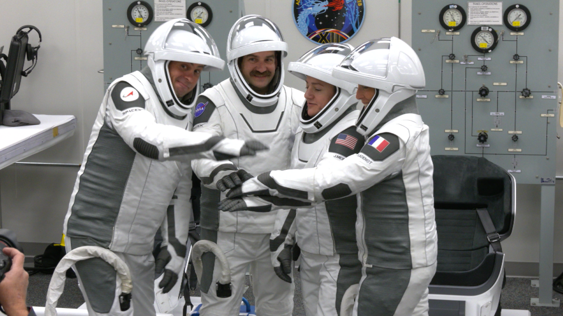 Image shows four astronauts in their white and black spacesuits stacking their hands in the middle before their launch to the International Space Station at 515 a.m. EST Friday, Feb. 13. Photo credit: NASA