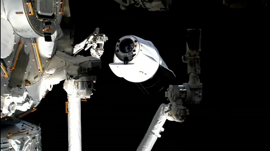 A SpaceX Dragon (center) backs away from the International Space Station after undocking from the Harmony module's forward port.