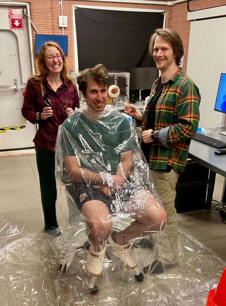 Ross Elder, Crew Health and Performance Exploration Analog (CHAPEA) Mission 2 commander, receiving a haircut from Ellen Ellis (left), CHAPEA mission 2 medical officer, and Matthew Montgomery (right), CHAPEA mission 2 science officer.