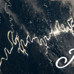 Sunlight can be seen glinting off the winding rivers across the Pampas grasslands of South America. The light forms a long winding shape from right to left across a dark blue background with patches of white clouds.
