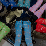 A group of people wearing different colorful socks posed in a circle with their feet all facing the center. They are floating in the picture because they are on the International Space Station on orbit.