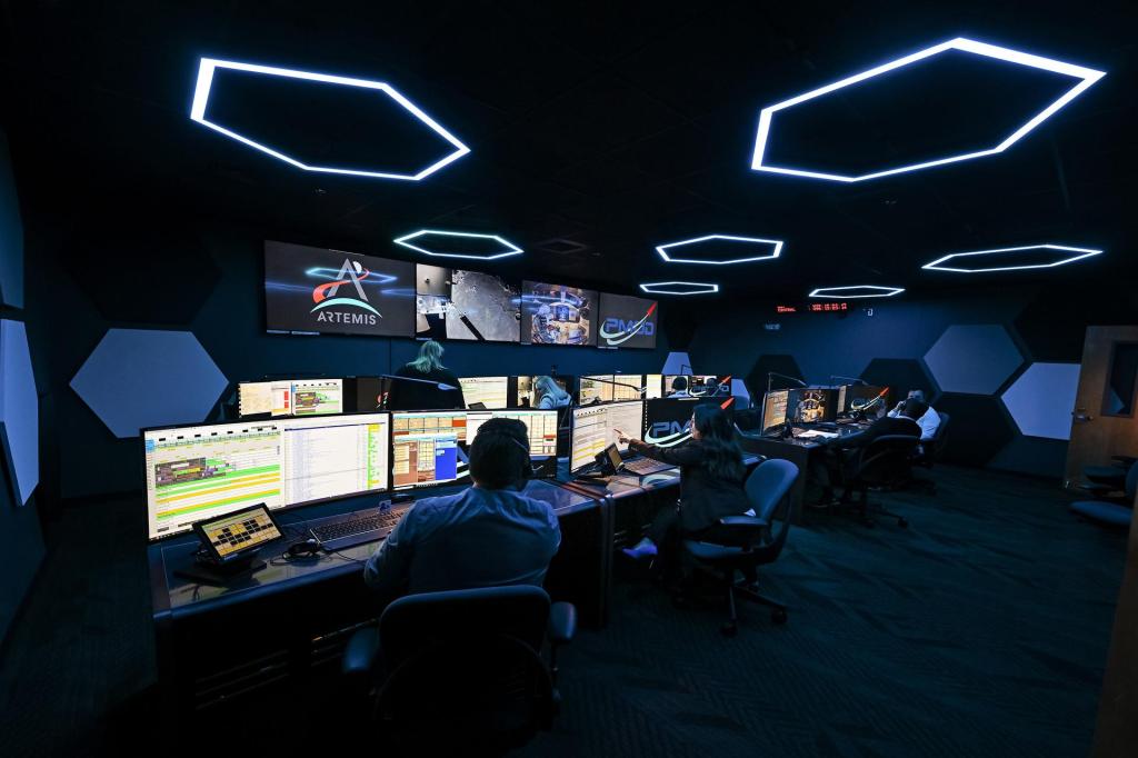 Two NASA engineers inside a dark control room looking at computer screens monitoring science operations.