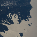 Lake Michigan beams in the afternoon sunlight as clouds blanket its southern tip—spanning Michigan, Indiana, and Illinois—in this photograph taken from the International Space Station while orbiting 263 miles above Earth. The northern tip of Lake Huron is visible at left.