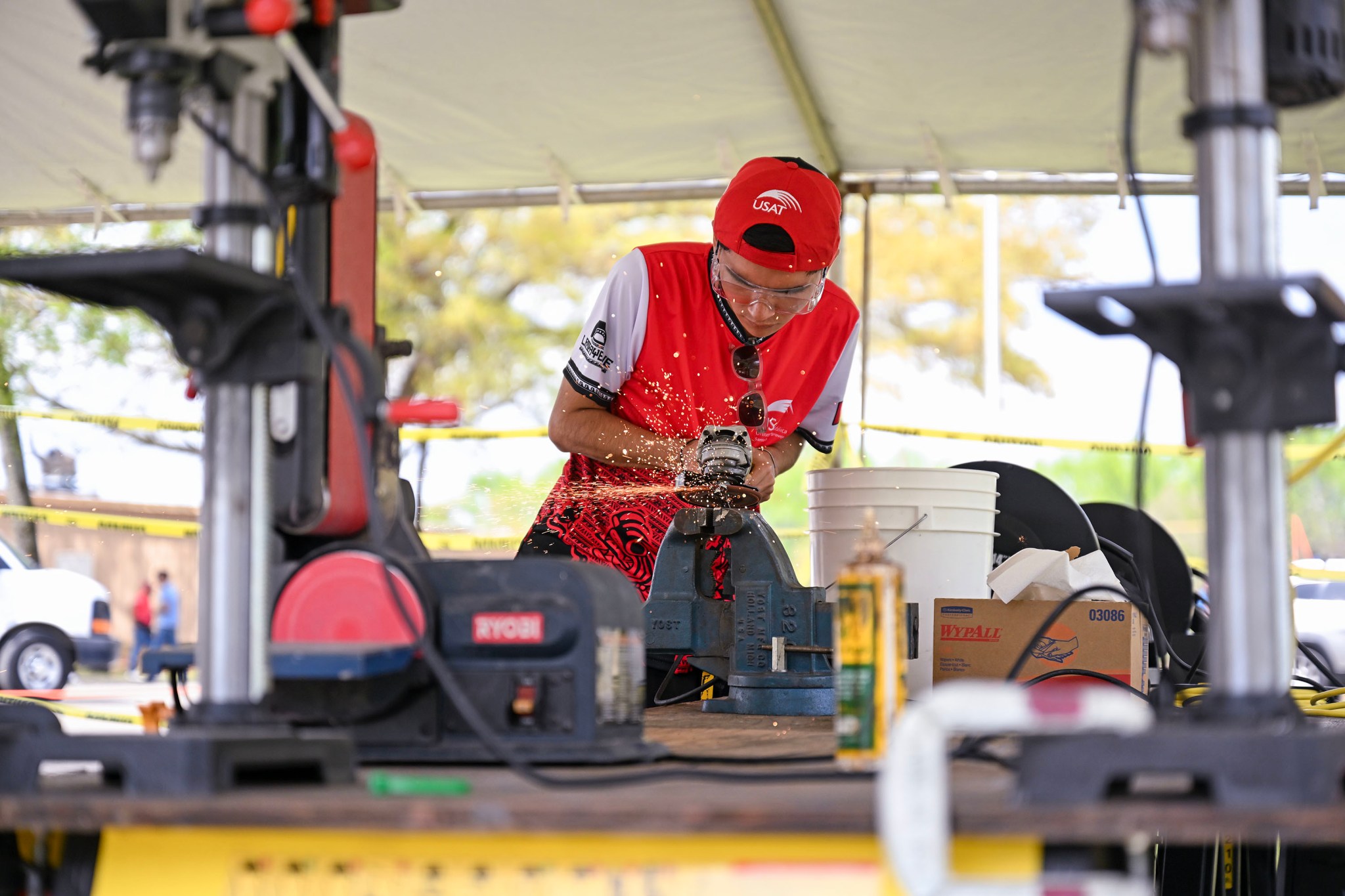 A student at the Human Exploration Rover Challenge using an electric sander