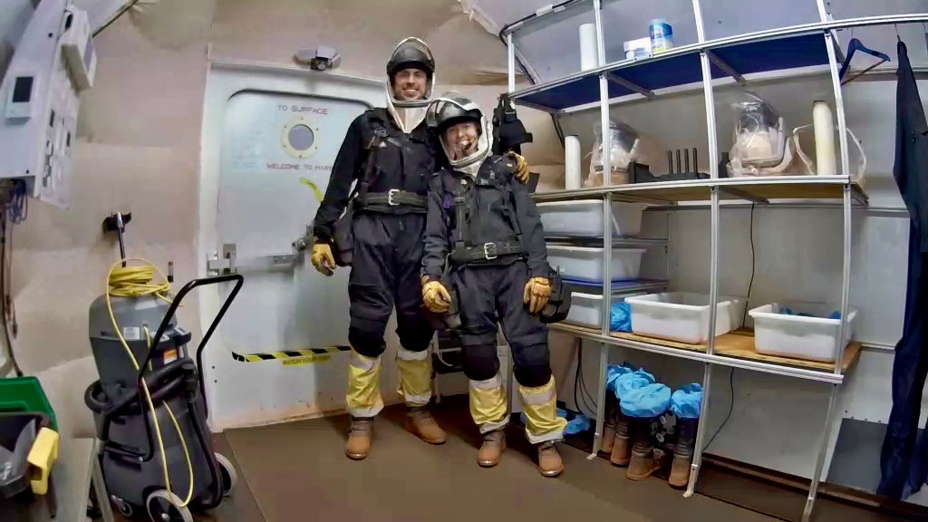 Crew Health and Performance Exploration Analog (CHAPEA) Mission 2 commander, Ross Elder, and CHAPEA Mission 2 medical officer, Ellen Ellis, stands in the airlock ready to go on EVA.