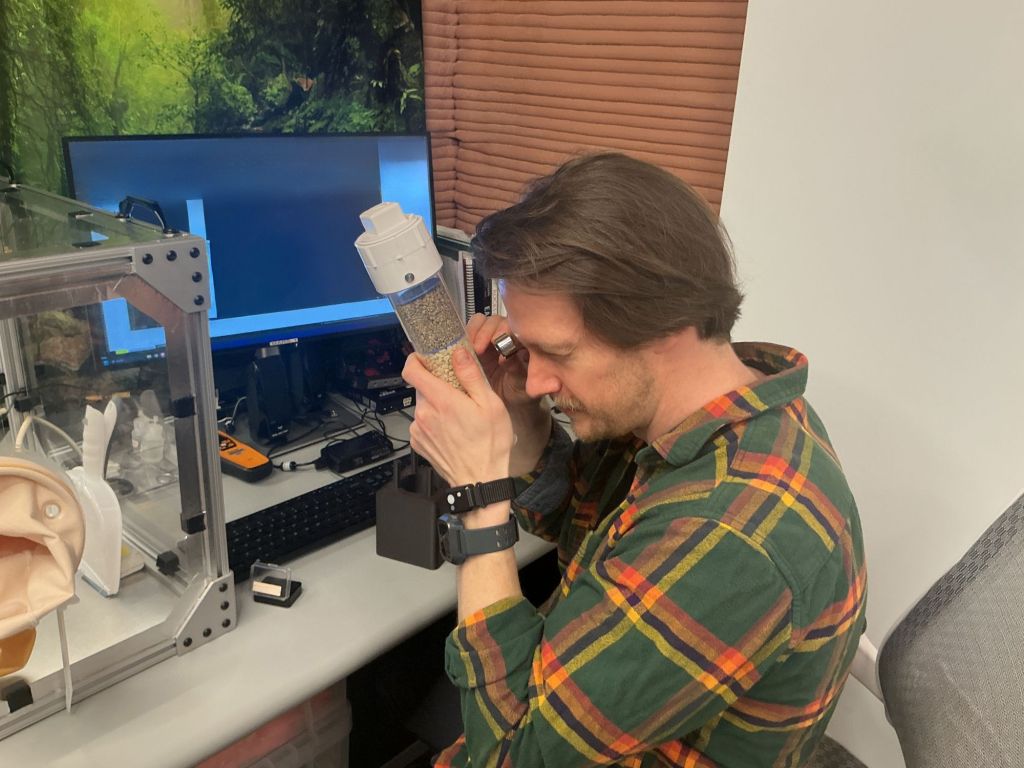 Matthew Montgomery, Crew Health and Performance Exploration Analog (CHAPEA) Mission 2 science officer, evaluates a geological sample near the habitat’s glove box.