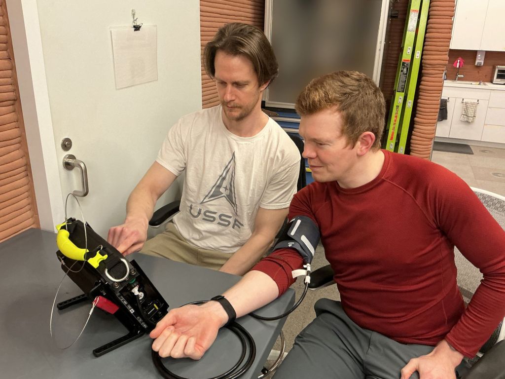 The Crew Health and Performance Exploration Analog (CHAPEA) Mission 2 crew test a specialized medical monitoring device that measures blood pressure and other health markers (from left: Matthew Montgomery, James Spicer).