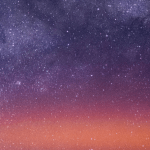 The Milky Way spans the night sky above a bright orange-yellow airglow that blankets the city lights along the east coast of Africa, from Kenya to Somalia.