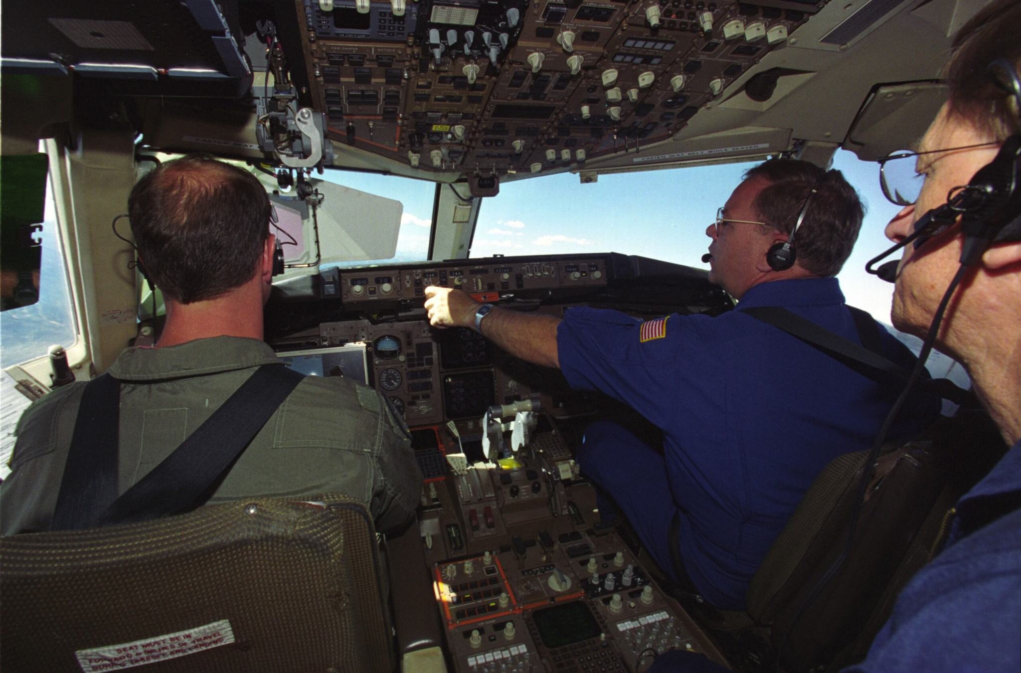 Three men in the cockpit of an airplane.