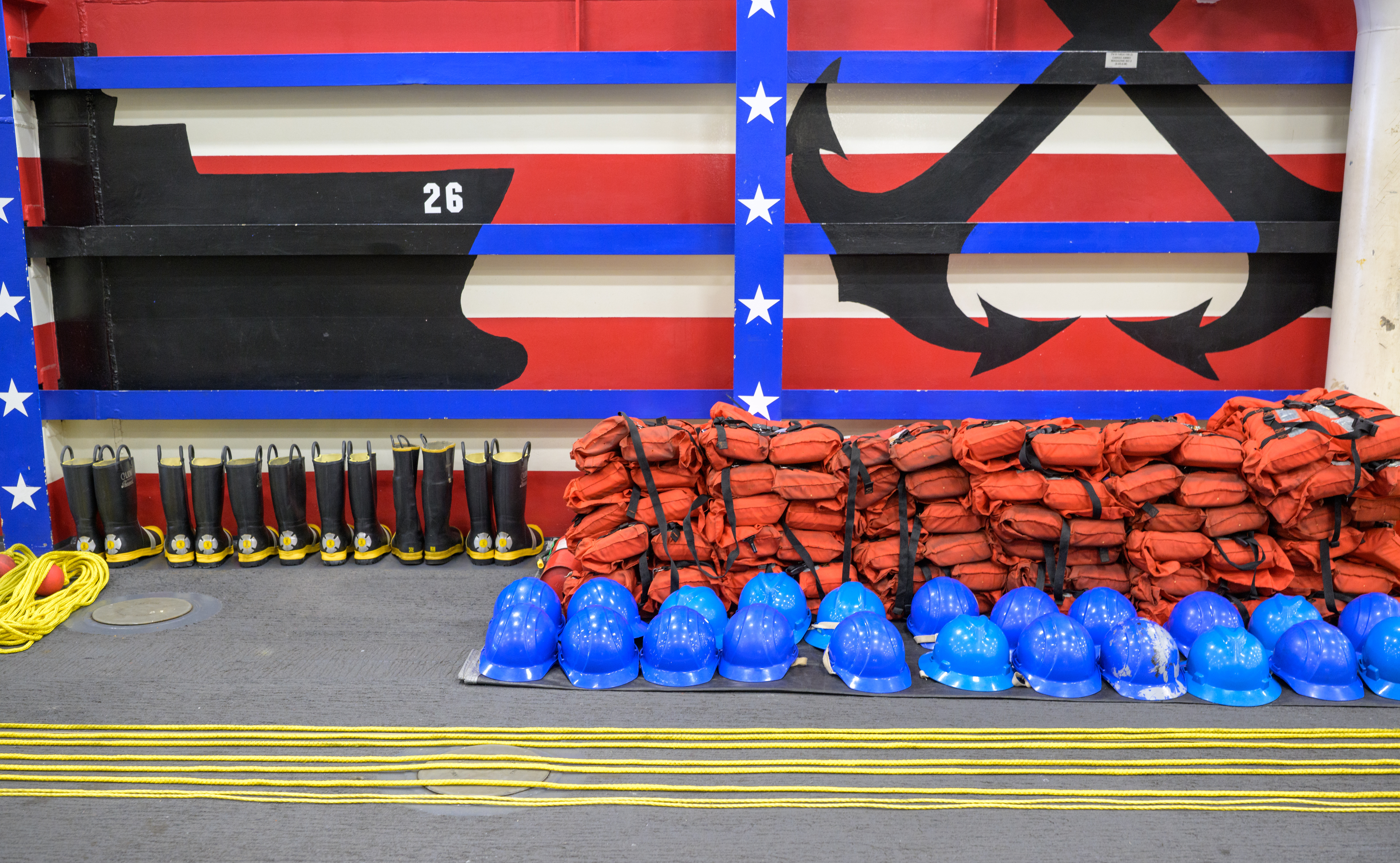Life jackets, helmets, throw ropes, and boots are seen laid out onboard USS John P. Murtha as NASA, U.S. Navy.,...