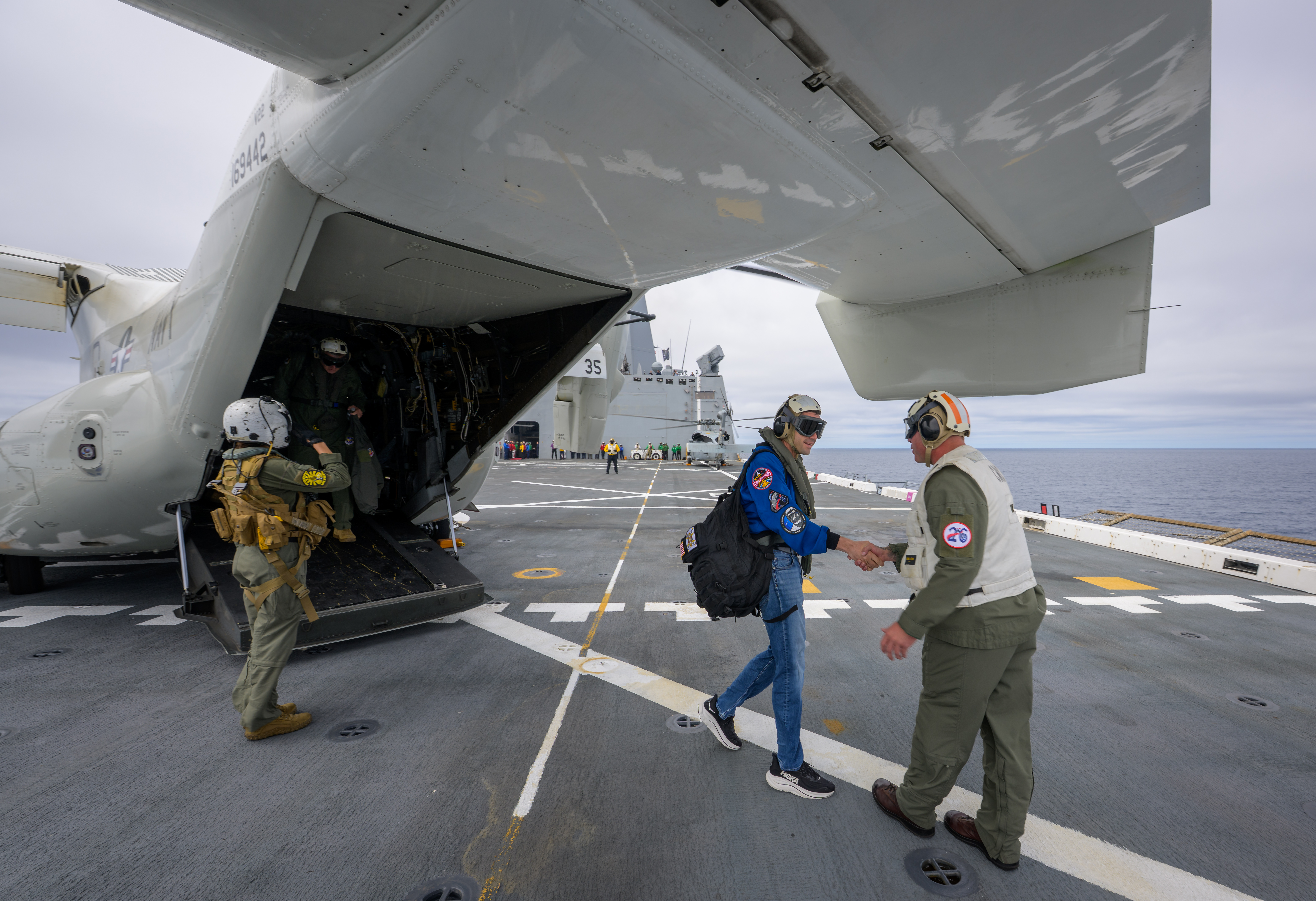 NASA Administrator Jared Isaacman, left, is greeted by Capt. Erik Kenny, commanding officer, USS John P. Murtha (LPD, after a...