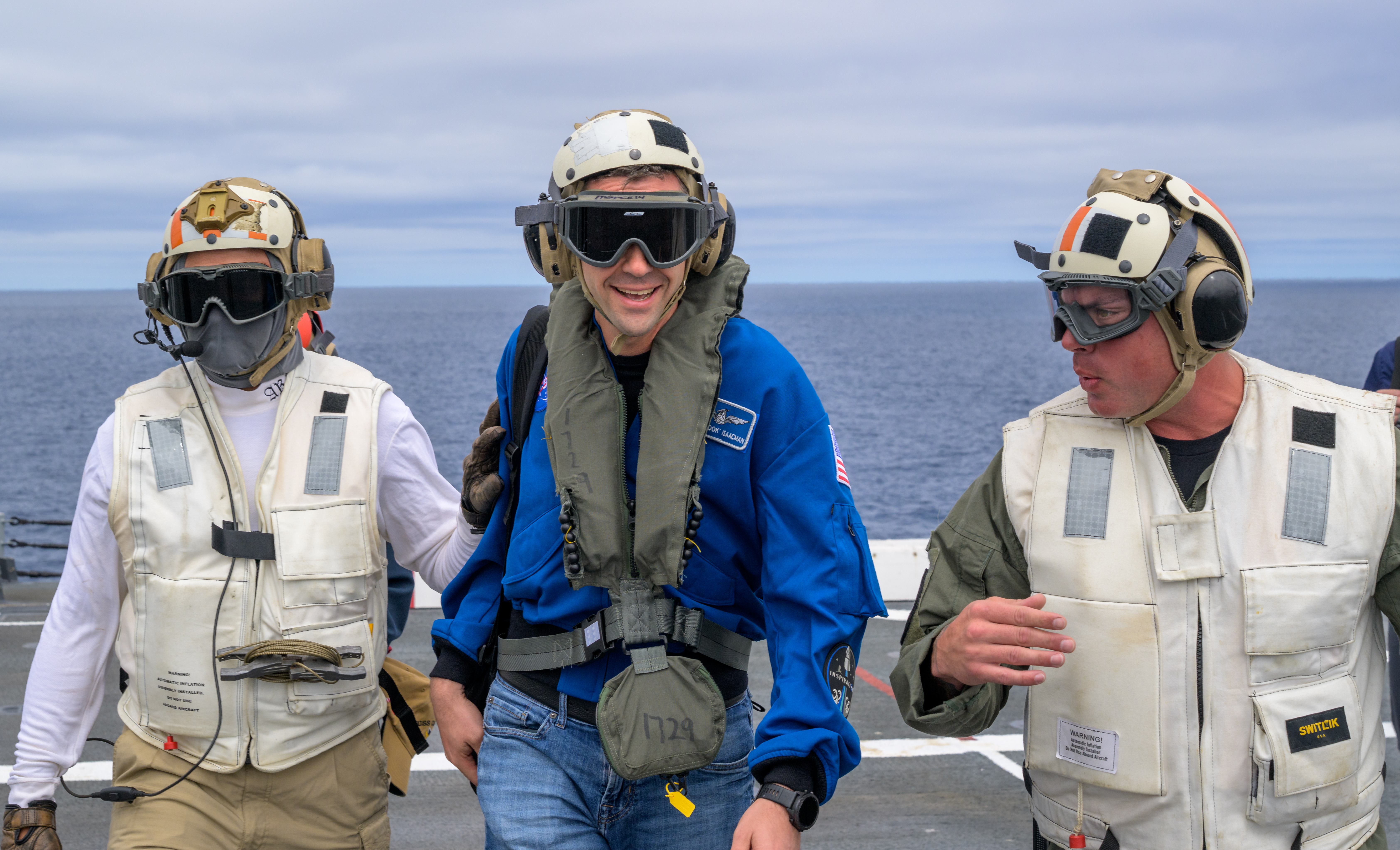 NASA Administrator Jared Isaacman, center, is greeted by Capt. Erik Kenny, commanding officer, USS John P. Murtha (LPD), right, after...