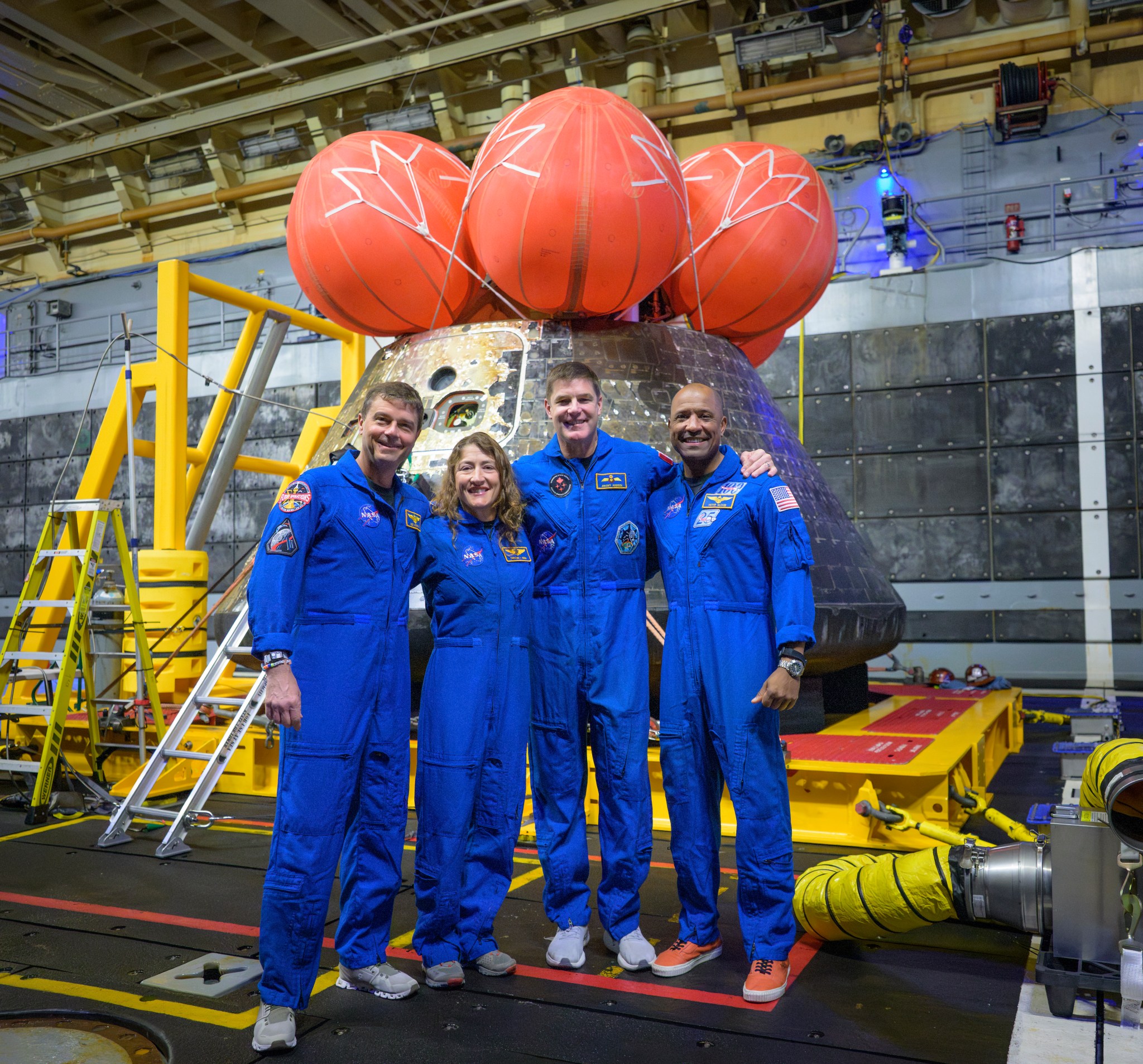 NASA astronauts Reid Wiseman, commander; left, Christina Koch, mission specialist; CSA (Canadian Space Agency) astronaut Jeremy Hansen, mission specialist; and NASA astronaut Victor Glover, Artemis II pilot, right, pose for a group photo after viewing the Orion spacecraft in the well deck of USS John P. Murtha, Saturday, April 11, 2026, in the Pacific Ocean off the coast of California. The quartet splashed down Friday, April 10 at 5:07 p.m. PDT (8:07p.m. EDT).