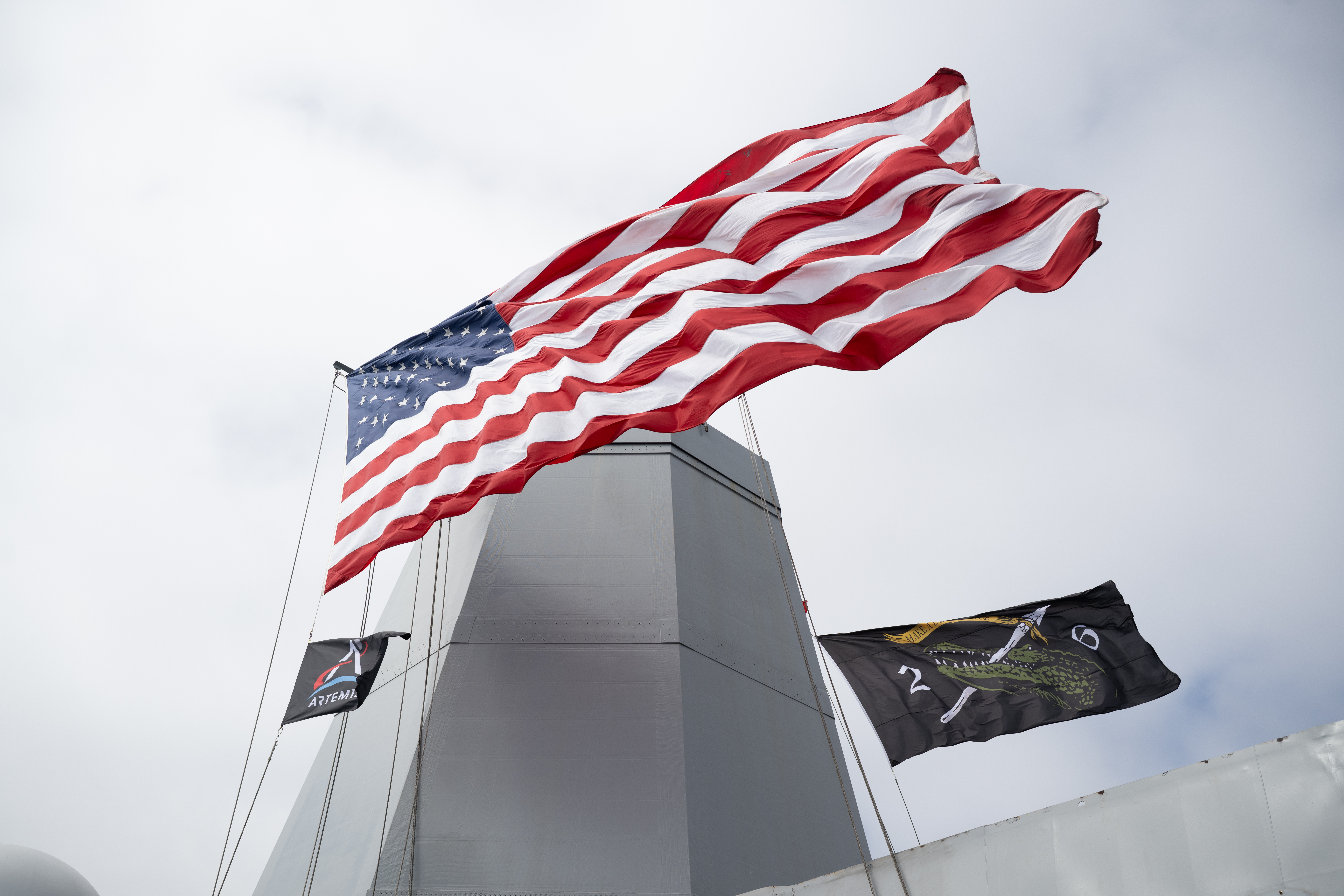 Flags are seen aboard USS John P. Murtha as teams prepare to recover mission crewmembers crew and NASA’s Orion spacecraft...