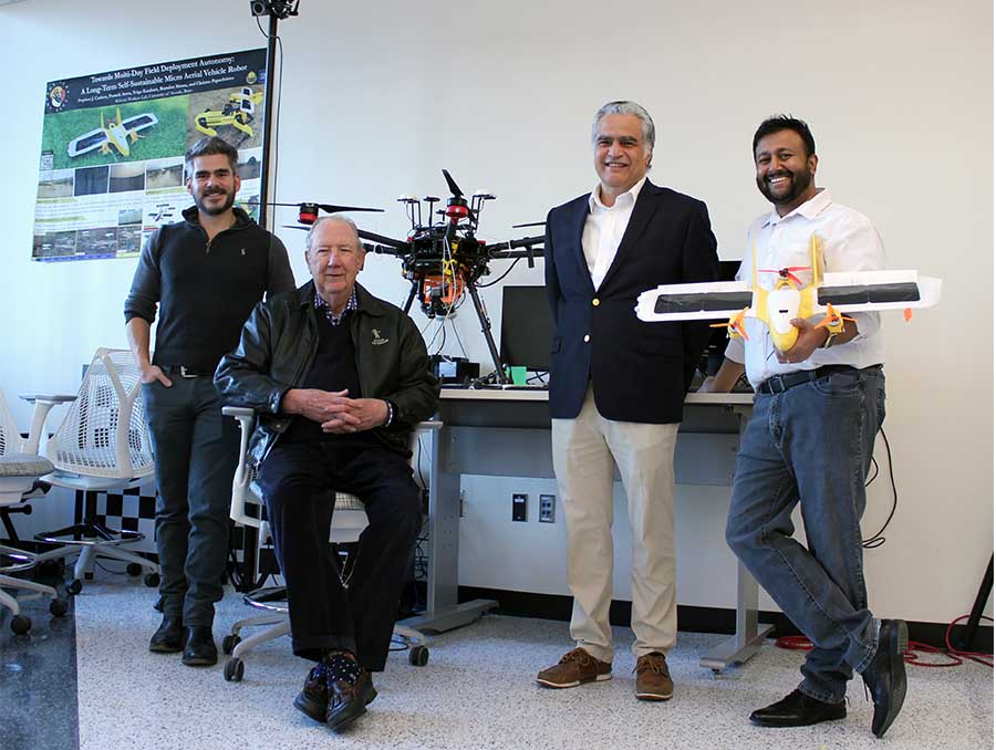 Assistant Professor Christos Papachristos; Gillemot Foundation trustee Tom Hall (seated); Professor Petros Voulgaris; and Assistant Professor Aditya Nair (holding a drone) post inside Papacristos' lab.