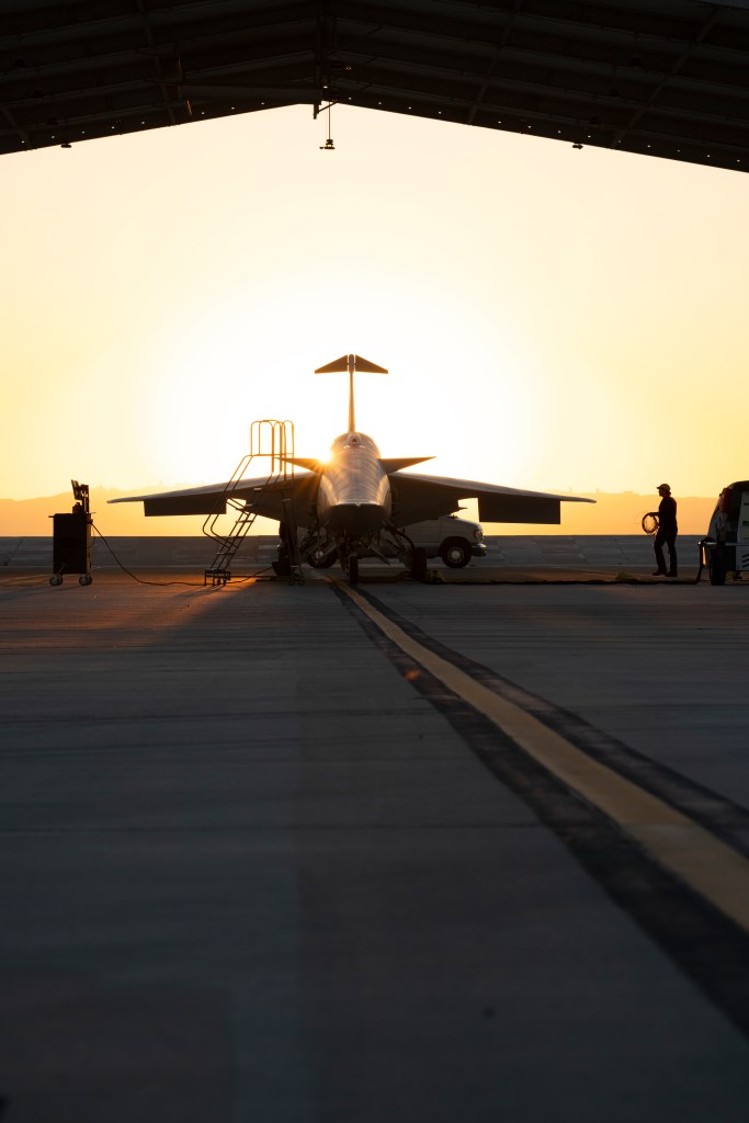 Face front view of NASA’s X-59 quiet supersonic research aircraft sitting in a run stall during sunrise.