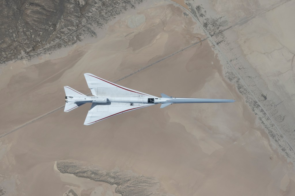 Aerial view looking down onto the X-59 while it's in flight over the Mojave Desert.