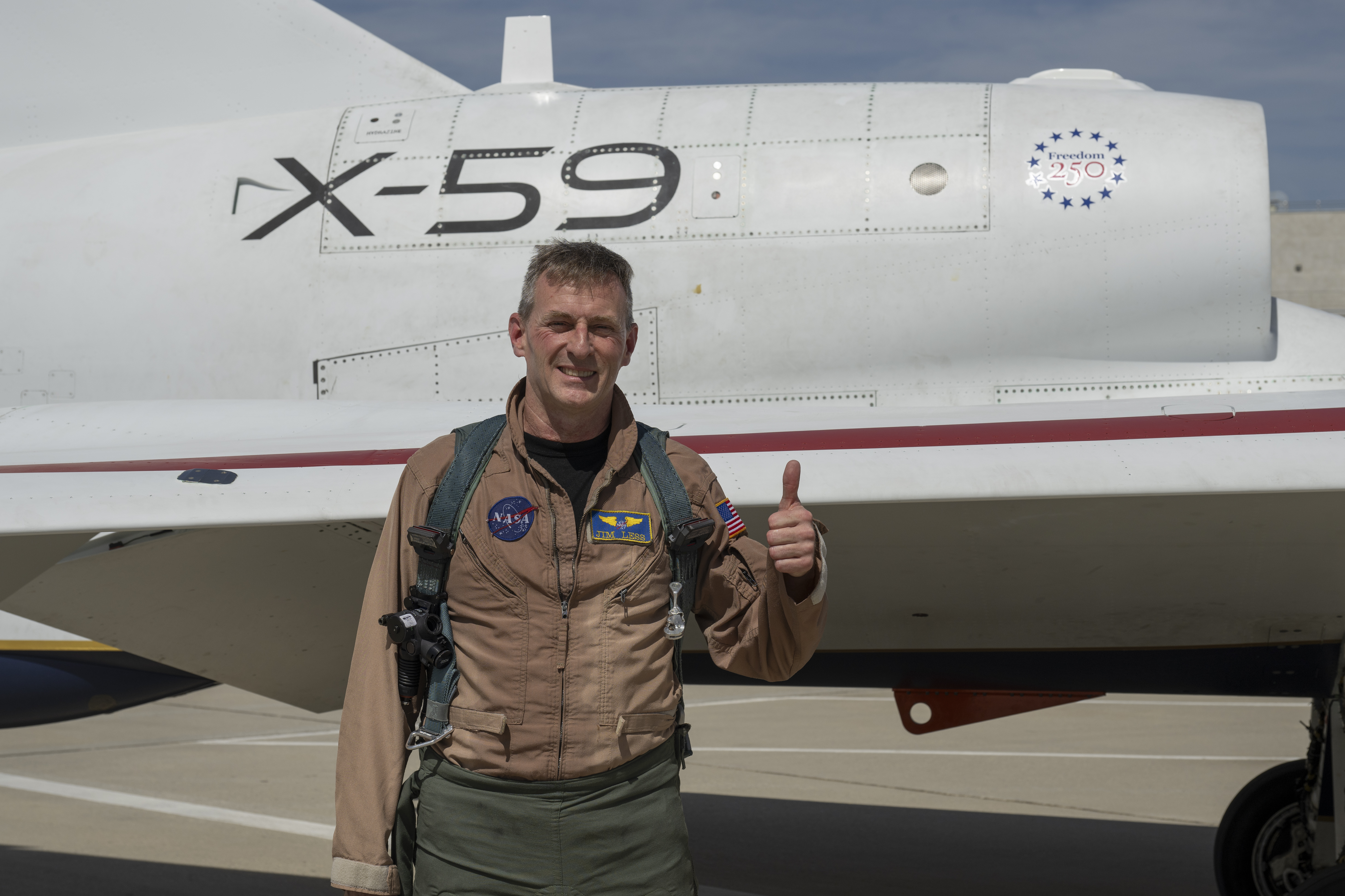 NASA's X-59 Test Pilot Jim "Clue" Less with a thumbs up in front of the X-59 fuselage.
