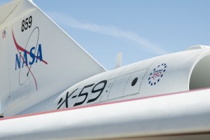 A close-up of NASA's X-59 tail showing a NASA graphic on the tail. "X-59" on the side of the jet engine, and a Freedom 250 logo toward the front of the engine.