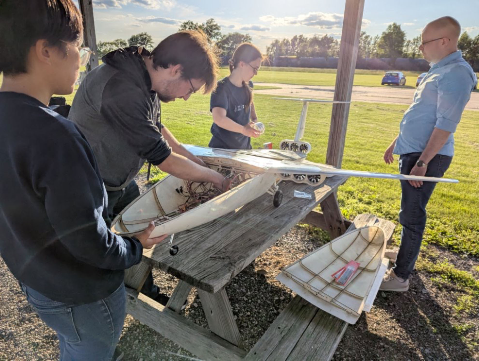 Students working on the CHEETA aircraft model outside on a sunny day.