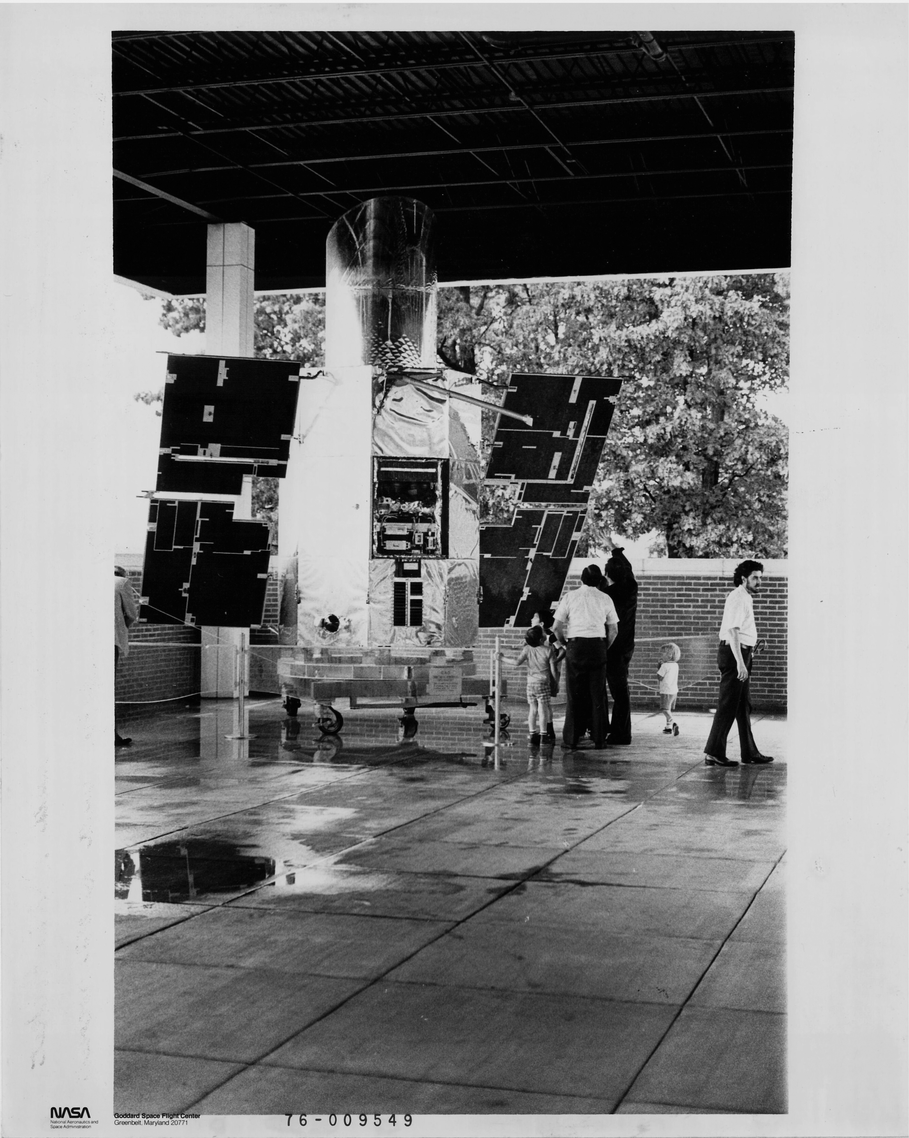 black-and-white photo of a large cylindrical satellite with two solar panel wings