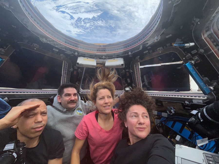 Expedition 74 flight engineers (from left) Chris Williams, Jack Hathaway, Sophie Adenot, and Jessica Meir are inside the International Space Station’s cupola, waiting to observe the plasma trail of the Orion spacecraft—with the Artemis II crew aboard—as it reenters Earth’s atmosphere.